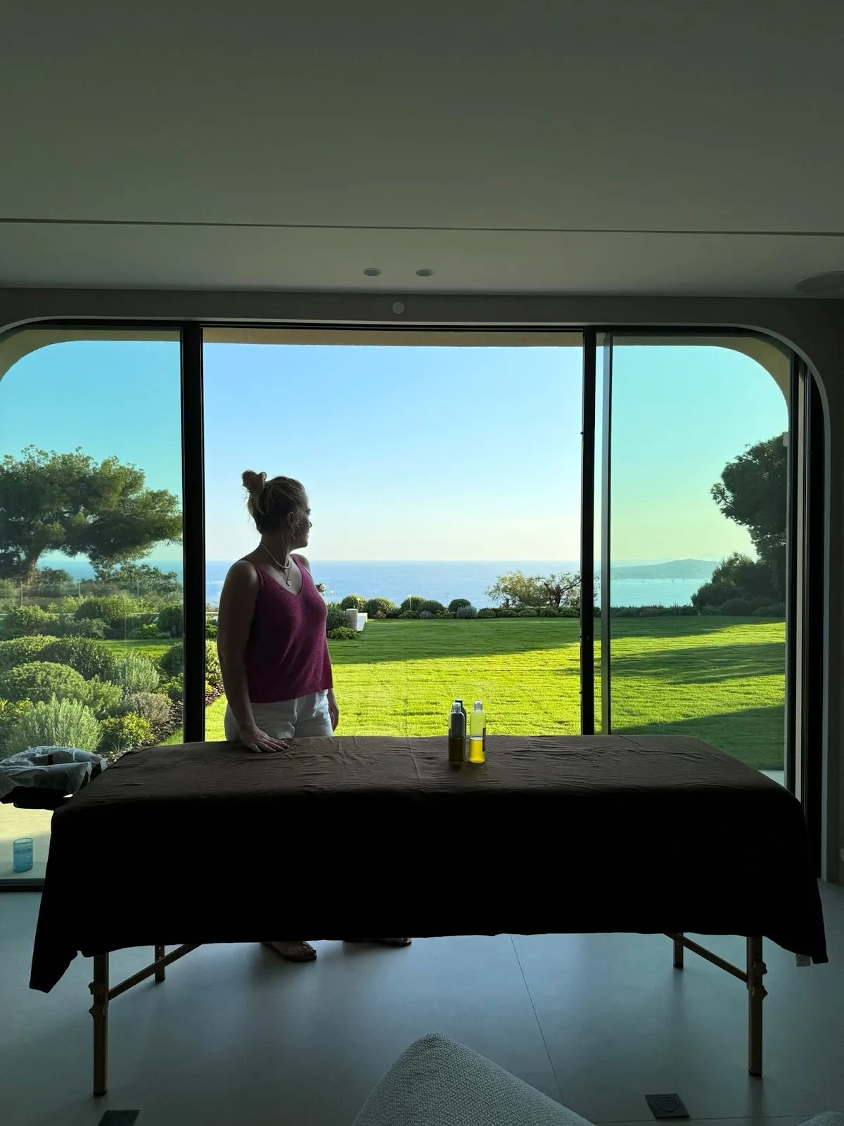 Camille près de sa table de massage dans une villa, jardin et mer en arrière-plan
